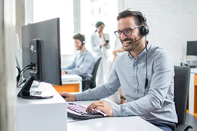 Mann mit Kopfhörern vor einem Computer Mann mit Kopfhörern vor einem Computer